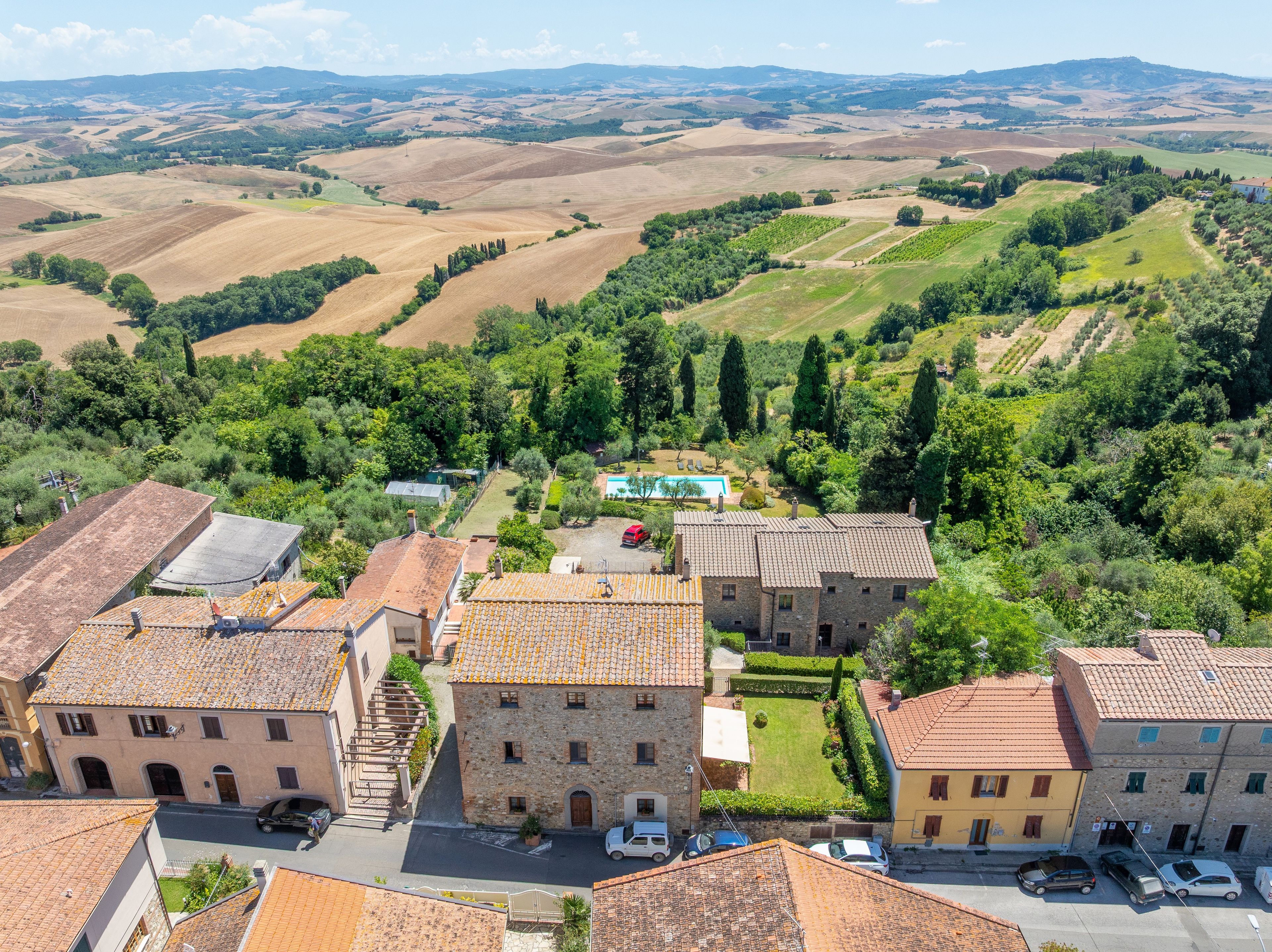 A rural village with stone buildings, a swimming pool, and terraced fields.