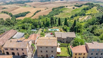 A rural village with stone buildings, a swimming pool, and terraced fields.