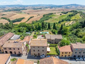 A rural village with stone buildings, a swimming pool, and terraced fields.