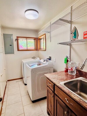A laundry room with a washing machine, a drying rack, and a sink with a countertop. - 17th Street Inn-Pawhuska (Pawhuska)