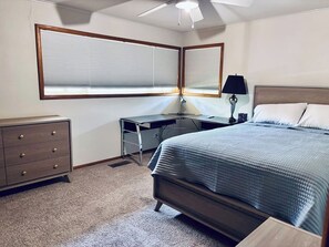 A bedroom with a bed, dresser, desk, and a ceiling fan. - 17th Street Inn-Pawhuska (Pawhuska)