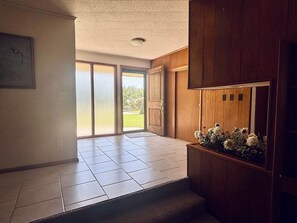 A room with a tiled floor, wooden paneling, a door leading outside, and a window with blinds. - 17th Street Inn-Pawhuska (Pawhuska)