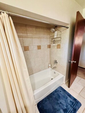 Une salle de bain équipée d’une baignoire, d’un espace douche et d’un porte-serviettes.