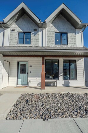 A two-story house with a garage, a front door, and a driveway. - The Point Lodge | Cozy Invermere Getaway (Invermere)