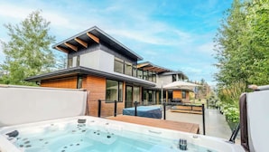 Ett modernt hus med ett bubbelbad, en träterrass och en uteplats.