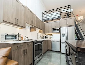 Eine moderne Küche mit Holzausstattung, einem Einbauofen, einer Mikrowelle, einem Kühlschrank und einer Edelstahl-Dunstabzugshaube.