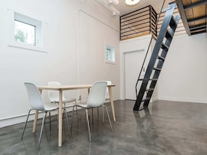 Ein Zimmer mit Tisch, Stühlen, einem Fenster, einer Tür und einer Treppe.
