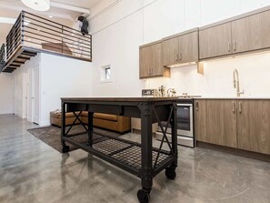 Eine moderne Küche mit Holzausbau, einem Edelstahlbackofen und einem schwarzen Metallrollwagen.