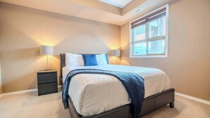 A bedroom with a bed, bedside tables, lamps, and a window.