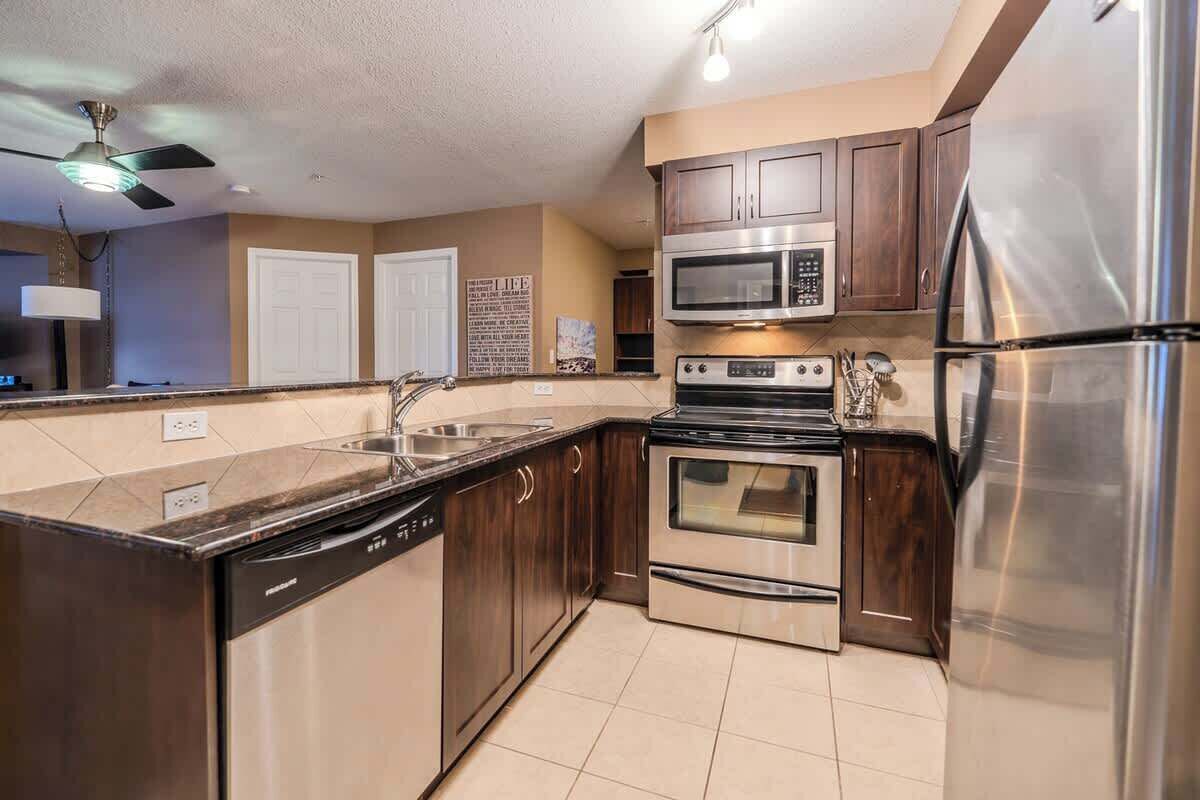A modern kitchen with stainless steel appliances, a dishwasher, and wooden cabinets.