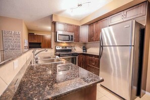 Eine moderne Küche mit Granit-Arbeitsplatten, Edelstahlgeräten und Holzschränken.