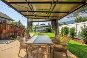 An outdoor patio with a covered seating area, a table, and chairs. - Backyard Oasis - Hot Tub, BBQ, Outdoor Bar (Invermere)