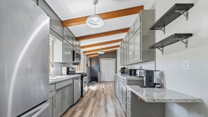 A modern kitchen with stainless steel appliances, wooden beams, and a central island. - 4 Bedroom cabin featuring breathtaking views and clean water just steps away! (Alexandria)