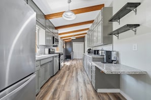 A modern kitchen with stainless steel appliances, wooden beams, and a central island.