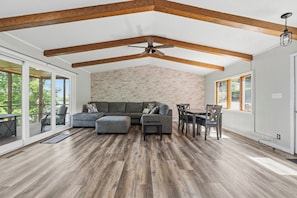 A spacious living area with a large sectional sofa, a dining table with chairs, and a ceiling fan.