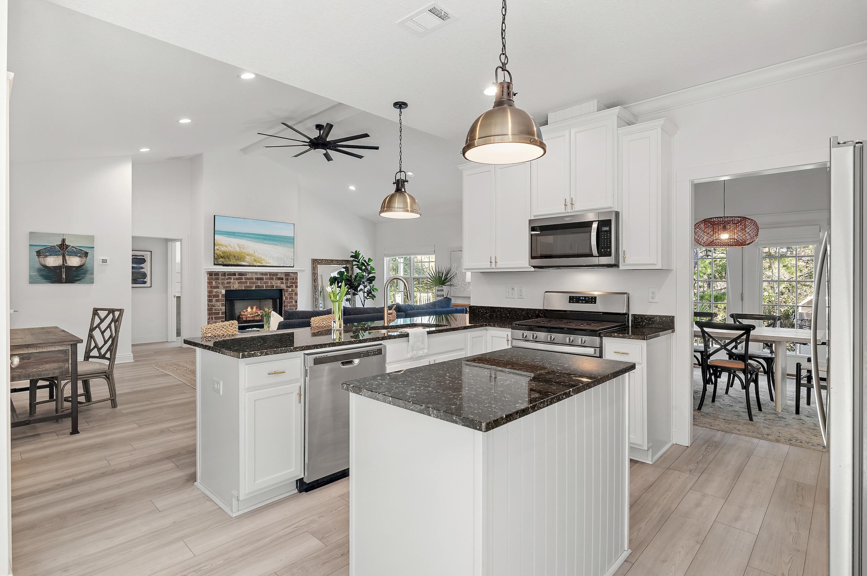 A modern kitchen with white cabinetry, a central island, stainless steel appliances, and pendant lighting.