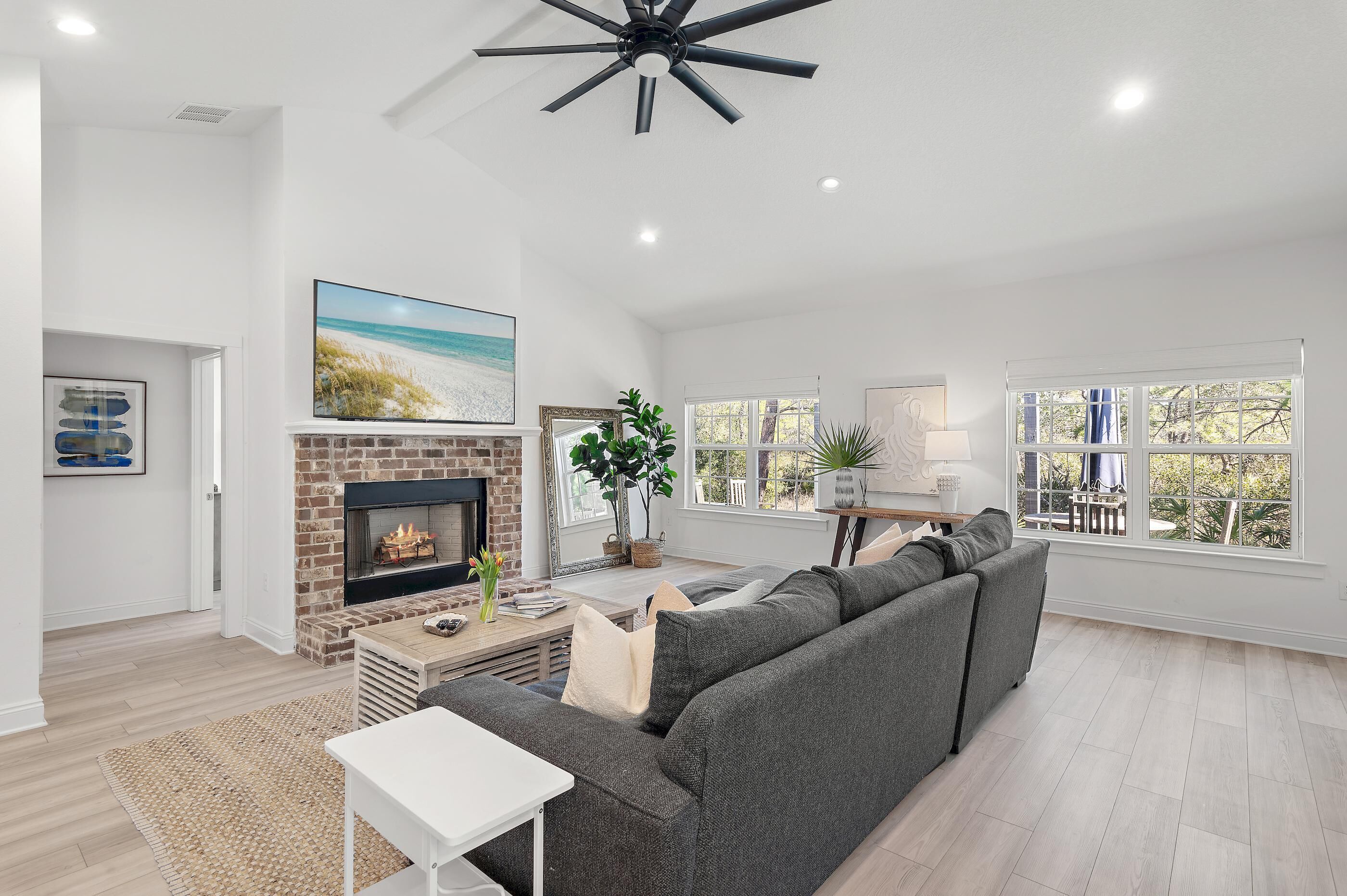 A spacious living room with a fireplace, a large sofa, a television, and a ceiling fan.