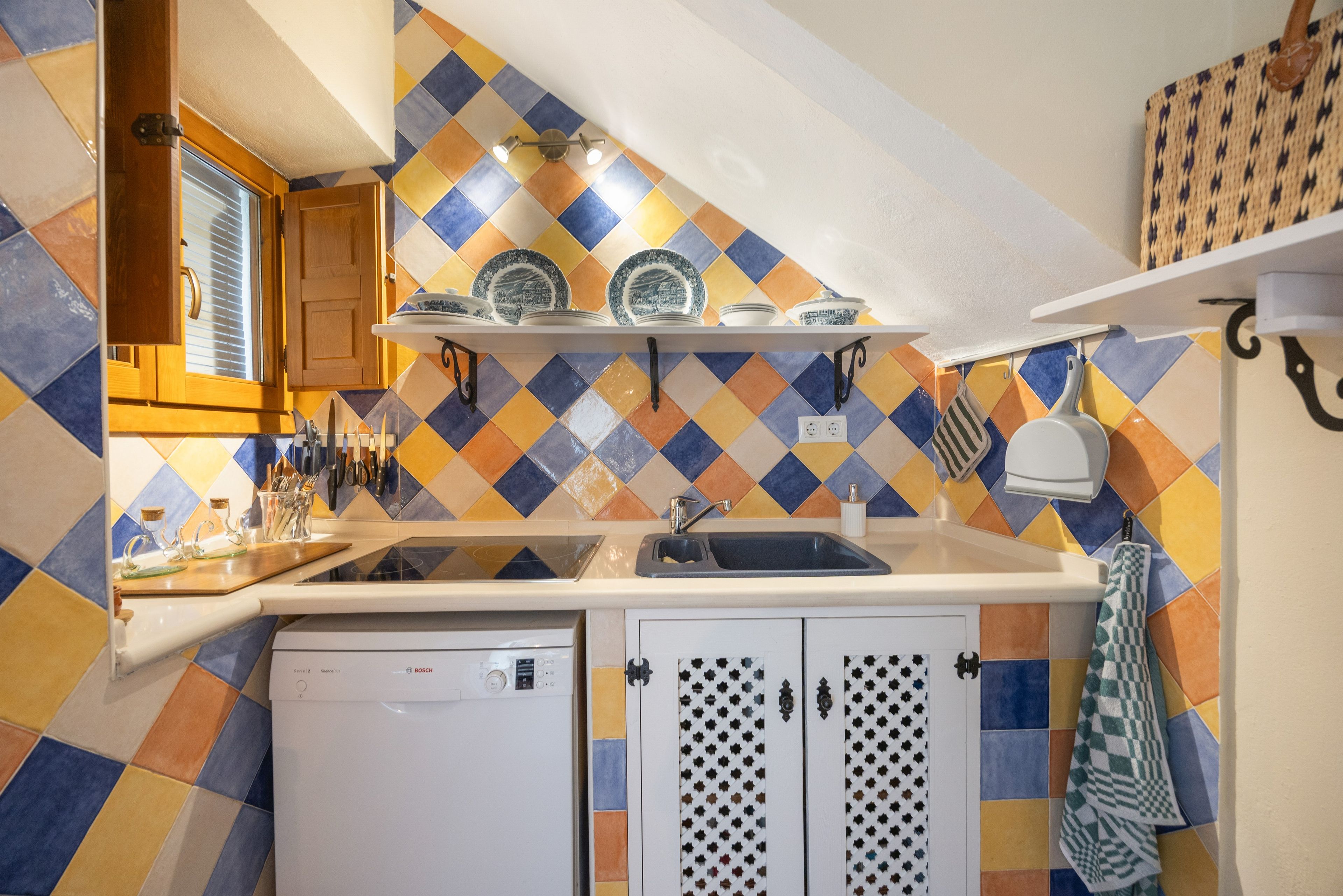 A compact kitchen with a dishwasher, a sink, and a countertop with various utensils.