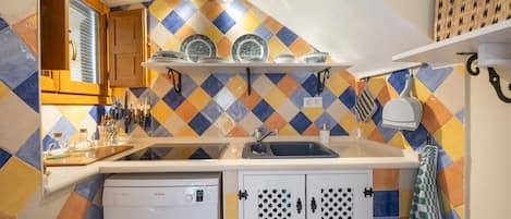 Cozinha compacta com máquina de lavar louça, pia e bancada com diversos utensílios.