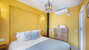 Et hotelværelse med en seng, et natbord, en vægmonteret aircondition og en dør.