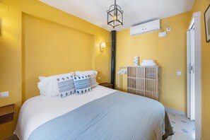 Quarto de hotel com cama, mesa de cabeceira, ar condicionado na parede e porta.