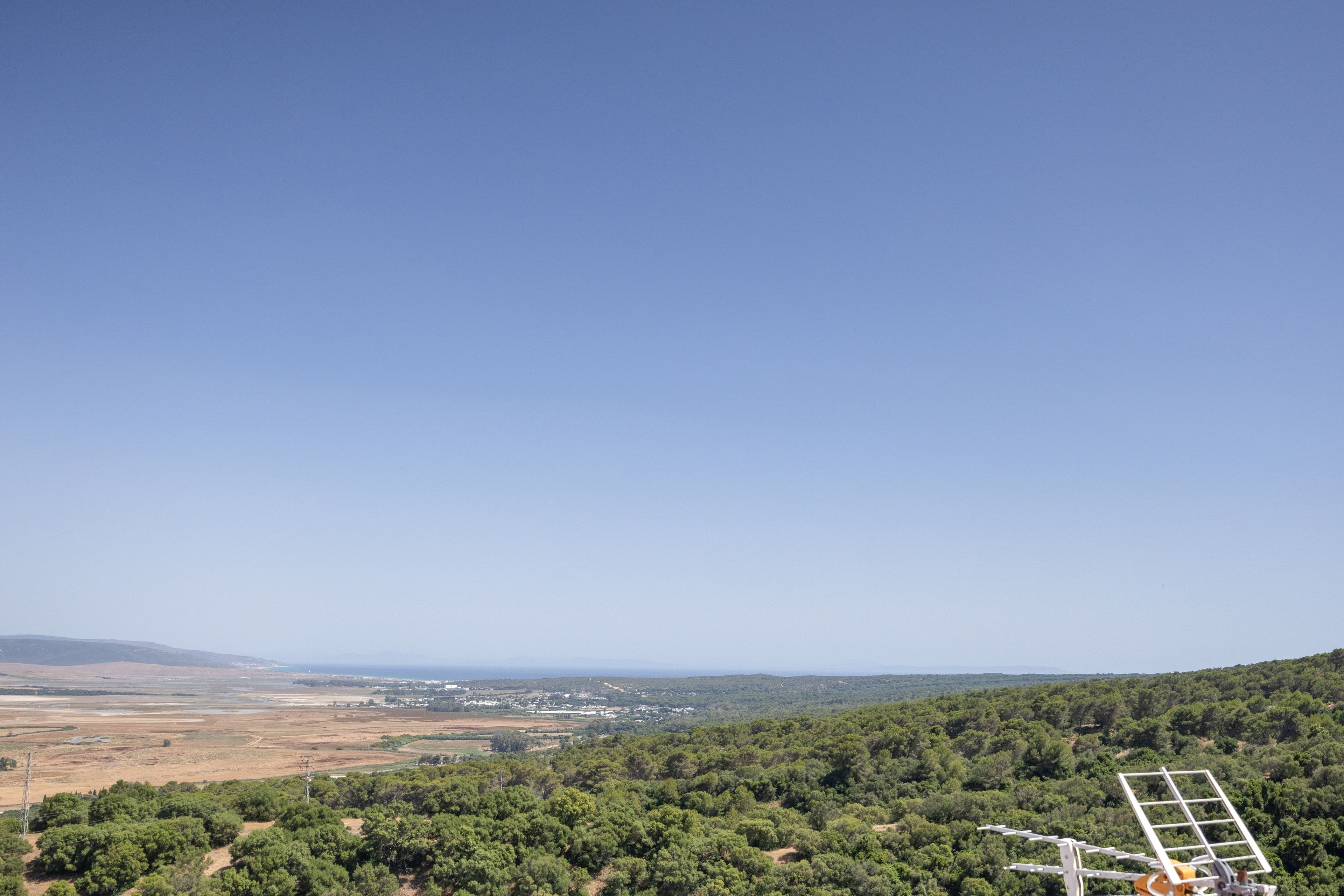 A landscape with a clear sky, a hilly terrain, and a solar panel structure.