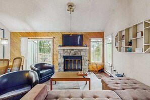 Ein Wohnzimmer mit Kamin aus Stein, Holzwänden und einem Fernseher.