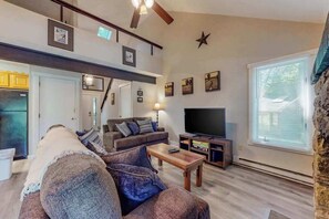 Ein Wohnzimmer mit Sofa, Couchtisch, Fernseher und einer Steinwand.