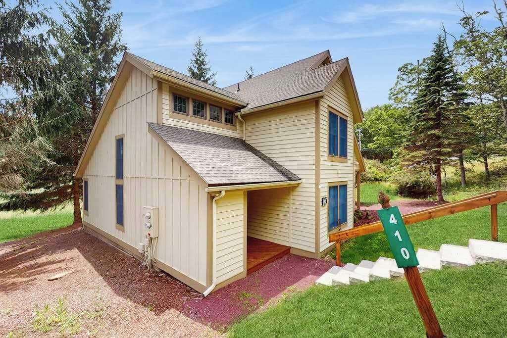 Une maison à deux étages avec un porche couvert, une porte d’entrée et une boîte aux lettres.