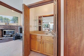 Eine Küche mit Holzschränken, einem Glastregal und einem Kamin aus Ziegelsteinen.