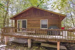 A wooden cabin with a porch, two windows, and a barbecue grill. - Woodland Cabin with Firepit, Pools & Lake Beach (Albrightsville)
