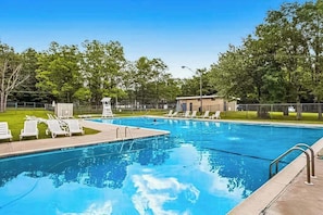 A swimming pool with lounge chairs, a lifeguard tower, and a fenced area with trees. - Woodland Cabin with Firepit, Pools & Lake Beach (Albrightsville)