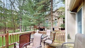 Eine überdachte Terrasse mit Gartenmöbeln, einem Grill und Blick auf ein bewaldetes Gebiet.