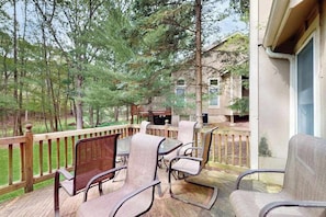 Eine überdachte Terrasse mit Gartenmöbeln, einem Grill und Blick auf ein bewaldetes Gebiet.