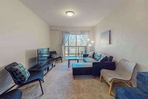 A living room with a sofa, chairs, a TV, and a window with curtains. - Gorgeous Townhouse with Fireplace Near Camelback (Tannersville)