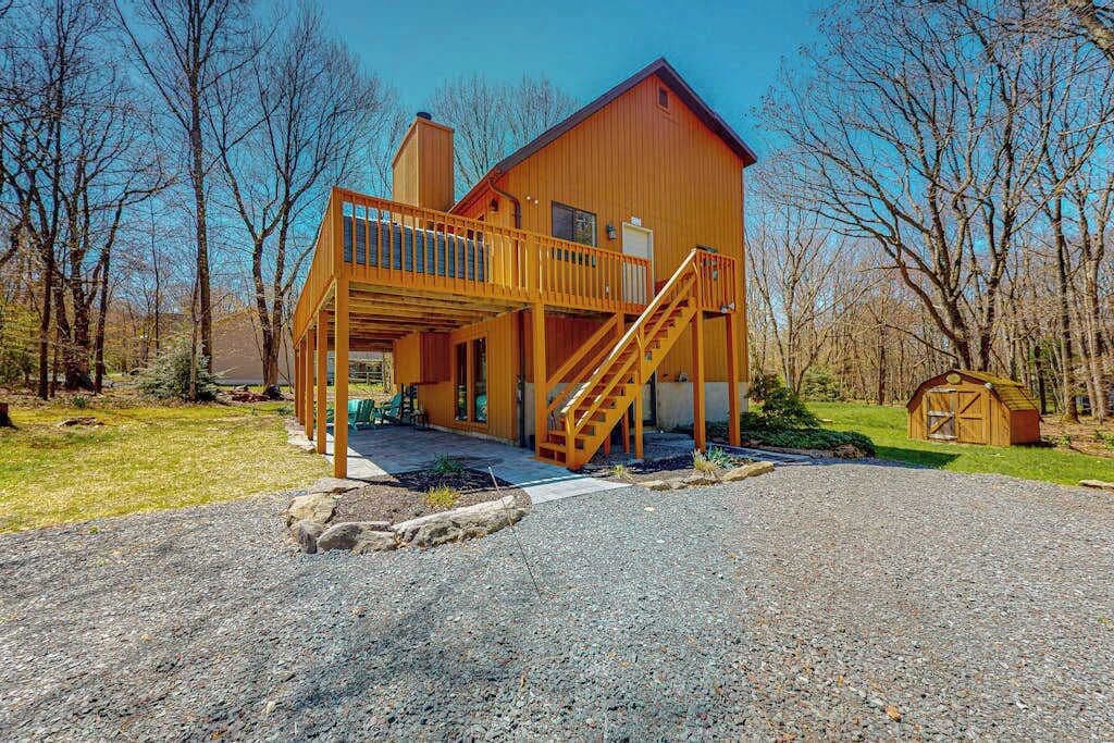 A wooden cabin with a balcony and a staircase leading to the main entrance.