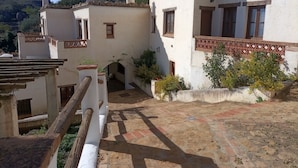 Ein Innenhof mit einem weißen Gebäude, das einen hölzernen Balkon und einen kleinen Bogenaufgang besitzt.