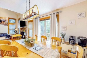 Ein Essbereich mit Holztisch, Stühlen, einer Kristallleuchter und einem Fernseher.