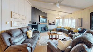 Una sala de estar moderna con sofás de cuero, una chimenea y ventanas amplias.