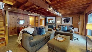 Interior acogedor de una cabaña con paredes de madera, chimenea y un cuadro de un oso.