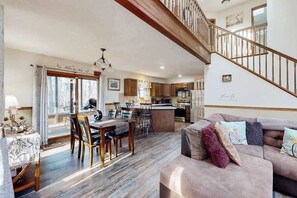 A spacious living area with a dining table, a sofa, and a staircase leading to an upper floor. - 3BR Spacious Dog-Friendly House (East Stroudsburg)
