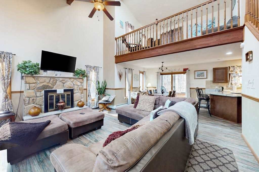 A spacious living room with a fireplace, a television, and a staircase leading to an upper level.