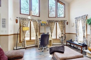 Habitación con escritorio, silla y un ventanal con cortinas.