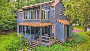 A two-story house with a porch, a covered deck, and a small shed.