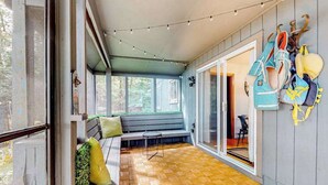 A covered patio with a wooden floor, a bench, and a wall-mounted rack with items.