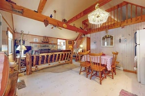 Ein rustikales Interieur mit einem Holzesstisch, Stühlen, einer Kristallleuchtre und einer Treppe.