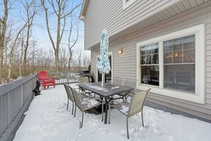 Eine Terrasse mit Tisch und Stühlen, ein rotes Stuhl und ein Grill.