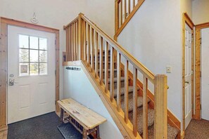 Eine Holztreppe mit einer Bank unten, einer Tür mit Fenster und einem an der Wand befestigten Schild.