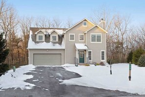 A two-story house with a garage, a front porch, and a driveway. - Cozy Home Near Waterpark - Hot Tub and Deck (Tannersville)