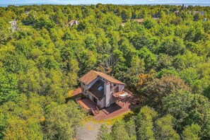 A single-story house surrounded by dense forest, with a visible deck and a clear sky. - Dog-Friendly Home with Hot Tub, Decks & Pool Table (Albrightsville)
